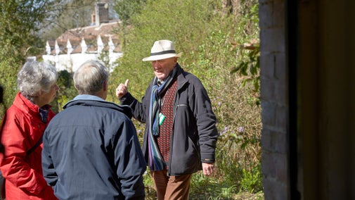 Volunteer talking to two visitors in the garden at Hardy's Cottage